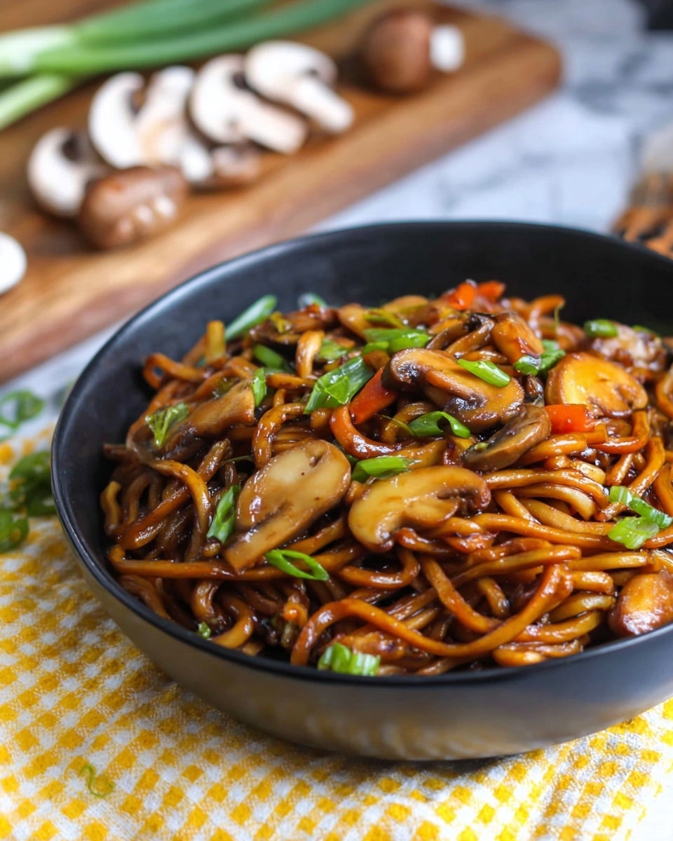 A deep black bowl holds a serving of thick, glossy, dark brown noodles mixed with slices of light brown cooked mushrooms, bright green chopped green onions, and small pieces of cooked orange carrots. The noodles look shiny and coated in sauce, with the mushrooms sitting near the top layer, some slightly browned. The green onions add fresh pops of color scattered on top. The bowl is placed on a white marbled surface with a yellow and white checkered cloth underneath. In the blurry background, green onions and sliced mushrooms rest on a wooden board. Photo taken with an iphone --ar 4:5 --v 7