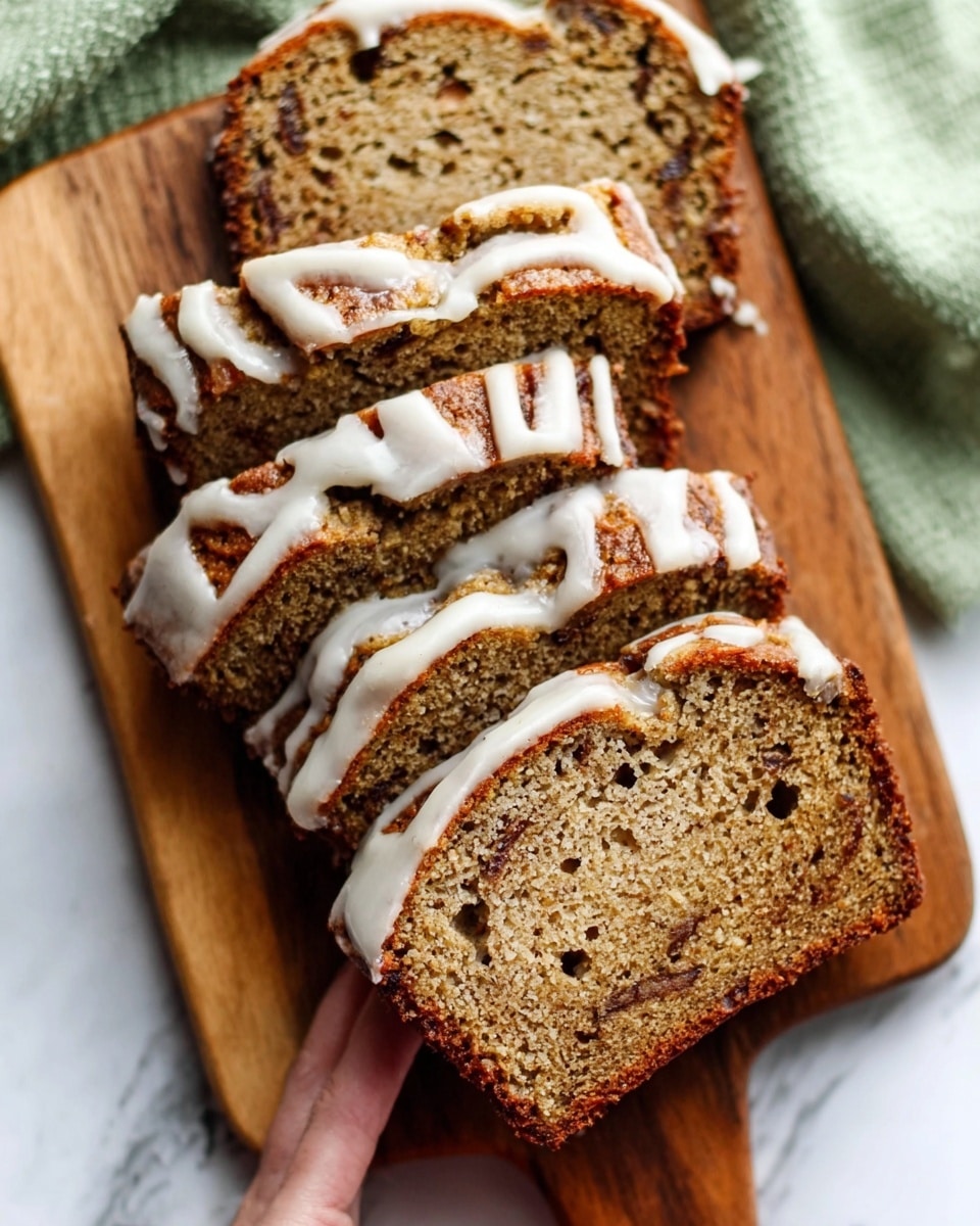 The image shows several slices of moist-looking banana bread arranged on a wooden cutting board with visible dark brown specks inside, indicating bananas or spices. Each slice has a thin layer of white icing drizzled on top in a flowing pattern. The bread has a soft texture with small holes and a browned crust on the edges. In the background, a light green cloth is placed on a white marbled surface, adding a touch of color contrast to the warm tones of the bread. A woman's hand is just visible, gently holding one slice at the bottom right of the image. Photo taken with an iphone --ar 4:5 --v 7