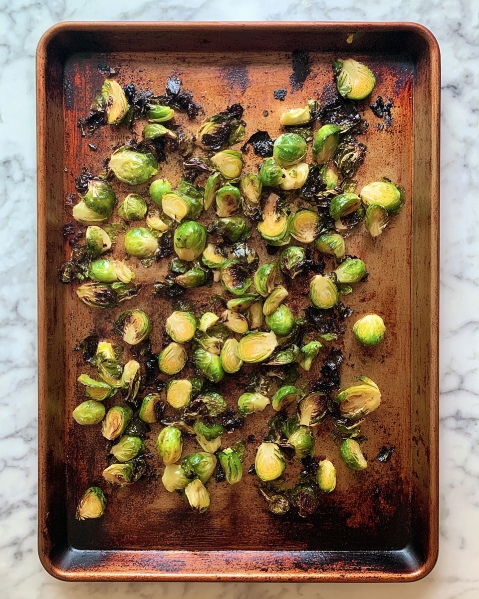 A rusty brown baking tray is filled with small, uneven pieces of roasted Brussels sprouts. The sprouts are mostly green with some yellow and have browned edges with black charred bits scattered throughout. The tray itself shows signs of use with dark stains and a worn texture. The scene is set on a white marbled surface. photo taken with an iphone --ar 4:5 --v 7
