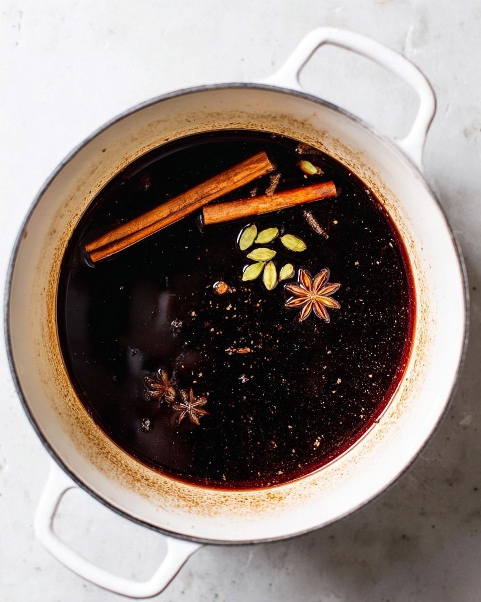 A white pot filled with a very dark brown liquid, almost black, with visible floating spices including two cinnamon sticks, green cardamom pods, and a star anise. The inner sides of the pot have light brown stains, and the pot sits on a white marbled surface. The contrast between the dark liquid and the white pot highlights the rich color and texture of the spices. photo taken with an iphone --ar 4:5 --v 7