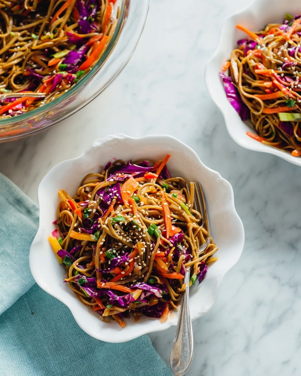 The image shows a noodle salad served in two white scalloped bowls placed on a white marbled surface. The noodle salad has a base layer of brown noodles mixed with vibrant orange carrot strips and bright purple cabbage slices layered evenly throughout. Small chopped green herbs and visibly sprinkled sesame seeds add texture and color on top of the noodles and vegetables. One bowl contains a silver fork resting on the edge, and a large clear glass bowl with more noodle salad is partially visible in the top left corner. A light blue cloth napkin is softly folded beneath one of the bowls. Photo taken with an iphone --ar 4:5 --v 7